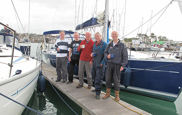A crew standing on a pontoon by a white yacht