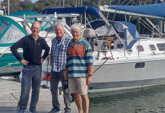 Three men standing in front of a yacht