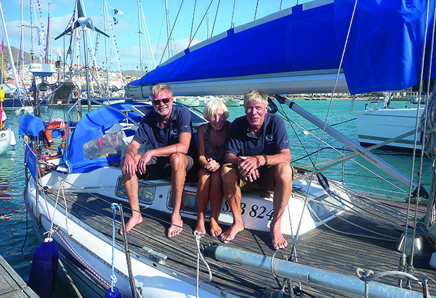 A woman and two men sitting on the deck of their yacht
