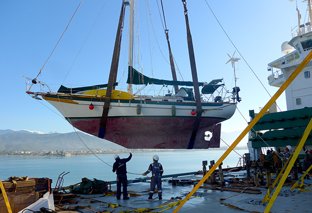 A yacht being craned onto a transporter ship
