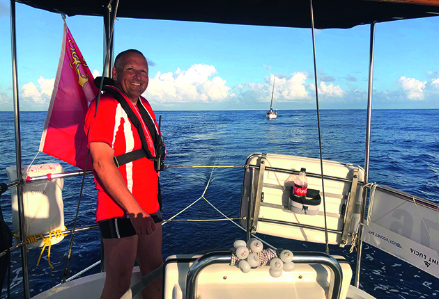 A man wearing a lifejacket on the back of a yacht which is towing another boat