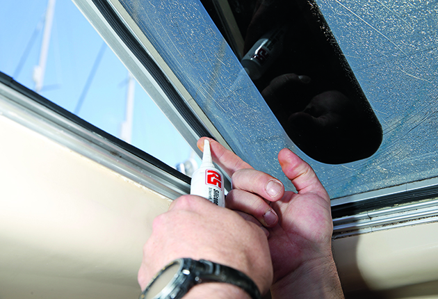 A person apply silicon grease to a hatch during a yacht charter holiday