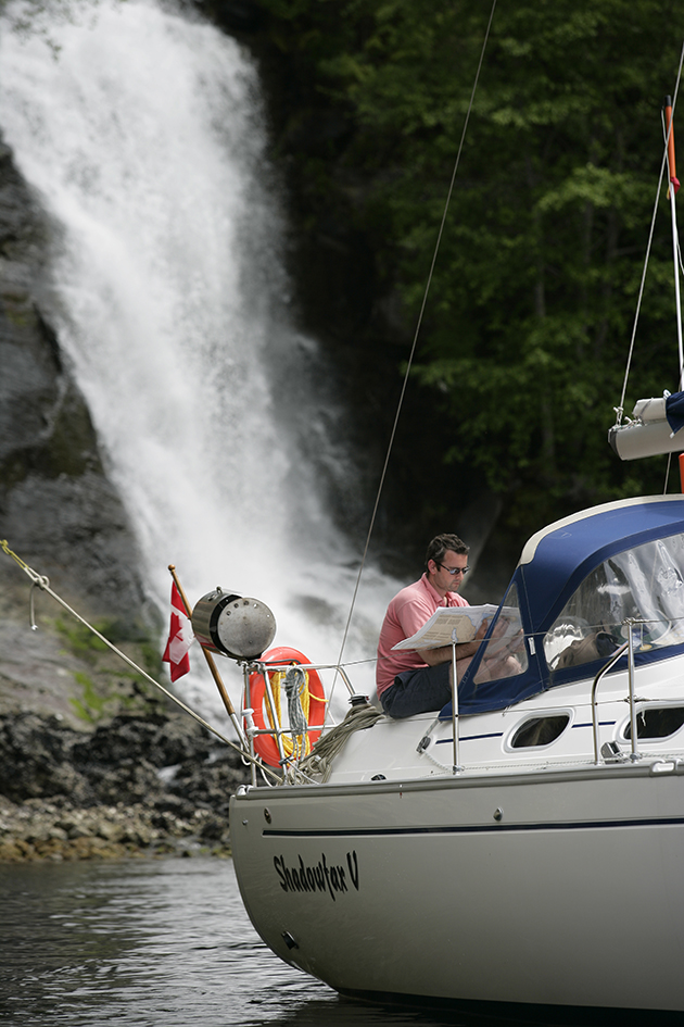 a yacht anchored by a waterfall