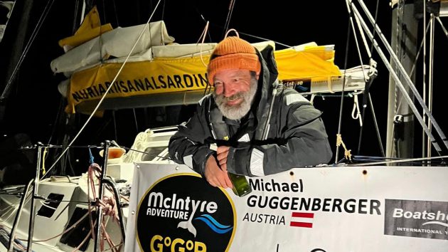 Michael Guggenberger wearing an orange hat and a black lifejacket leaning over his boat