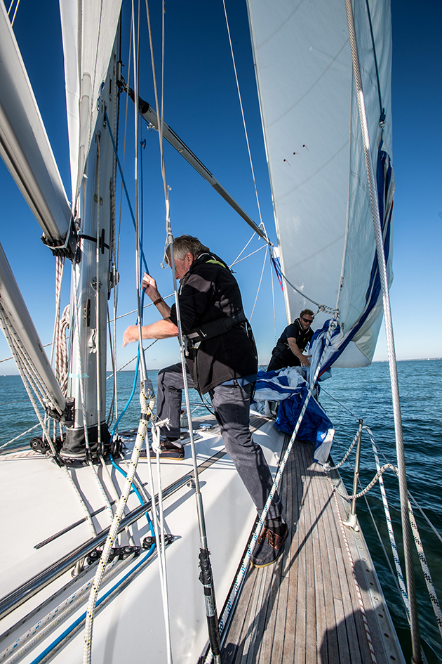 A crew pulling a line at the mast on a yacht