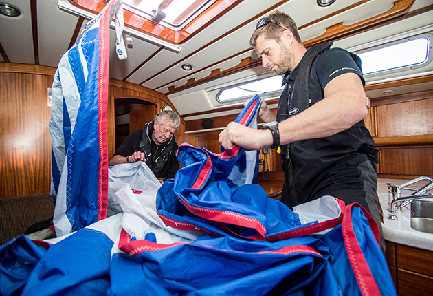 crew packing away a spinnaker on a yacht