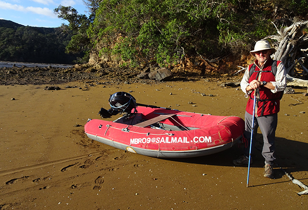 A man standing next to a dinghy which has dinghy chaps