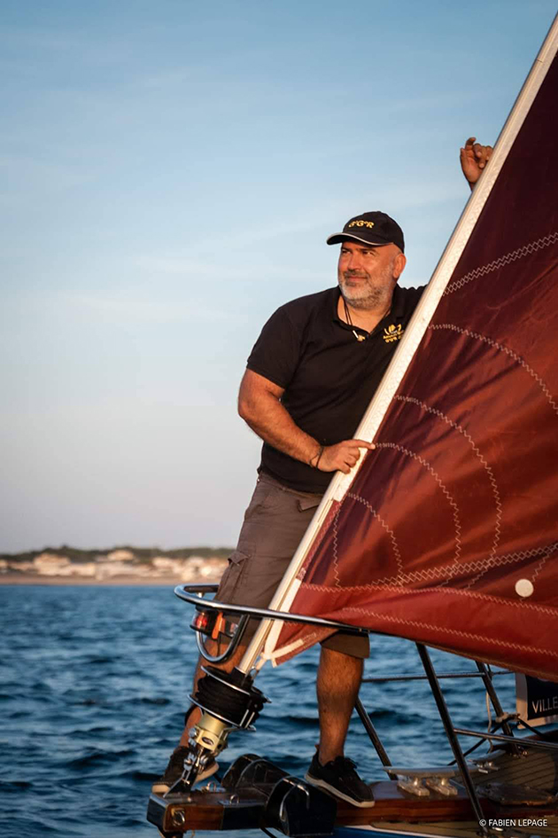 A skipper in a black tshirt and the bow of his boat