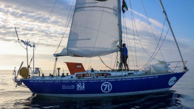 A man sailing a yacht with a blue hull