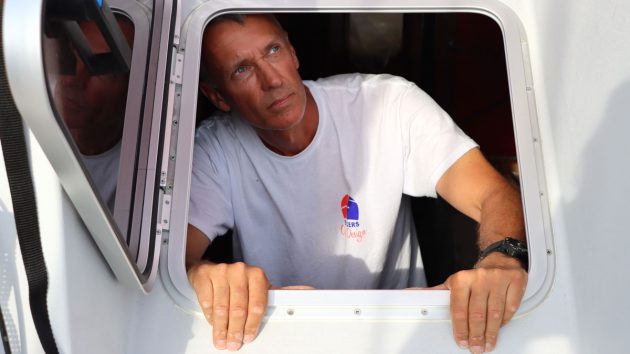 Guy Waites in a while tshirt looking out of a hatch on a boat