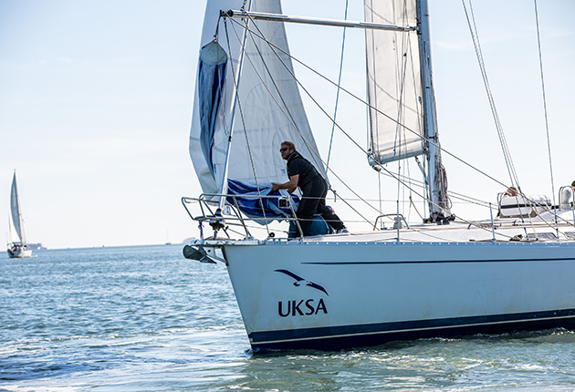 A crew member holding sail at the bow of a boat