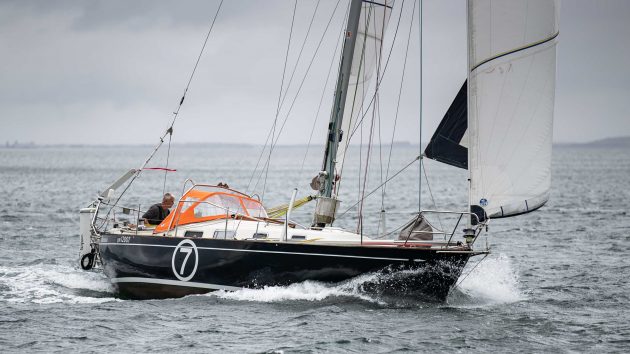 A man sailing a blue hulled yacht