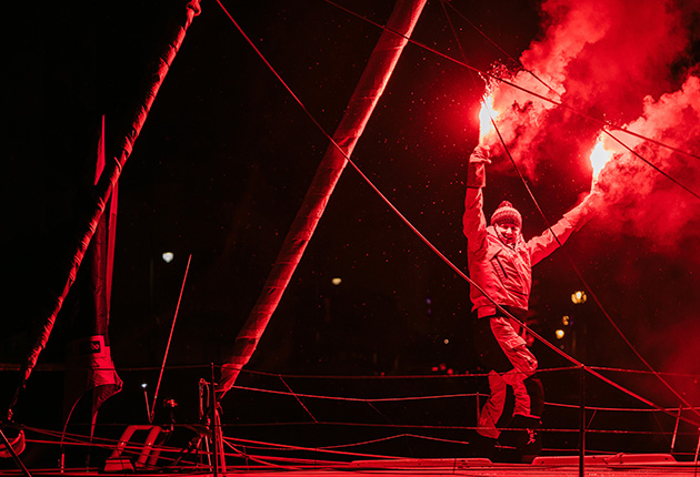 A skipper holding flares to celebrate finishing the Vendee Globe