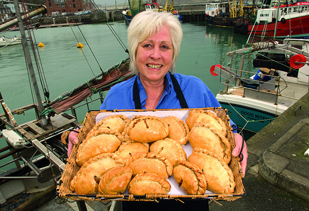 A woman holding a tray of Cornish pasties