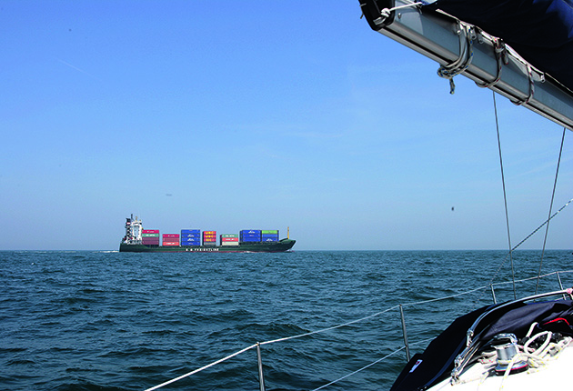 A cargo ship carrying containers as seen from a yacht