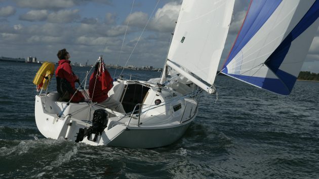 a man in red jacket and trousers sailing a boat