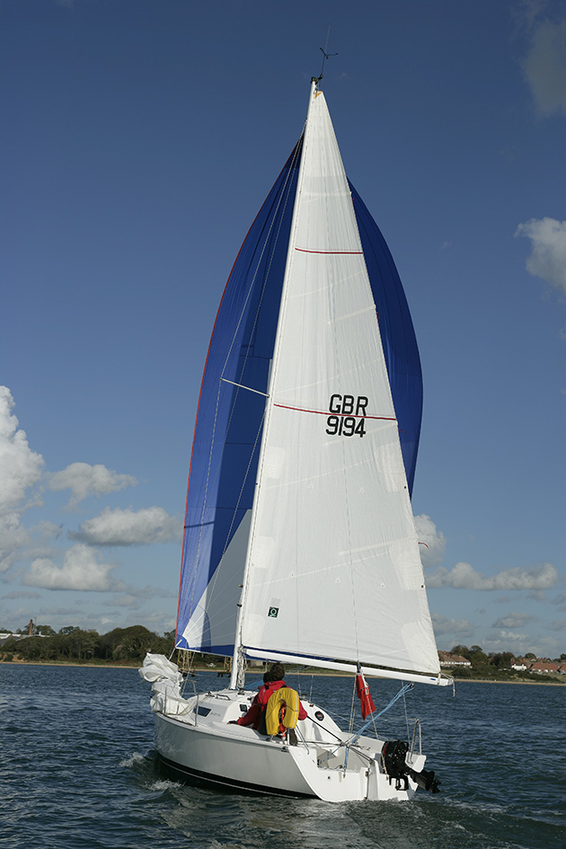 A white boat with blue and white sails