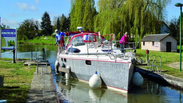 A boat with a grey keel with buoys motoring through the canals