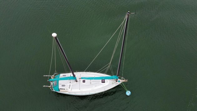 An aerial view of a yacht with a white deck with unstayed rigs