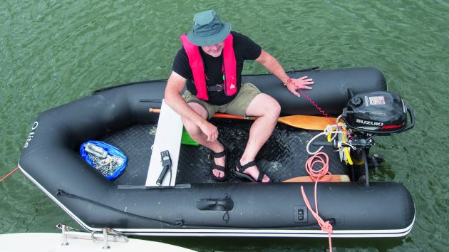 a man wearing a hat and a red lifejacket sitting in a dinghy